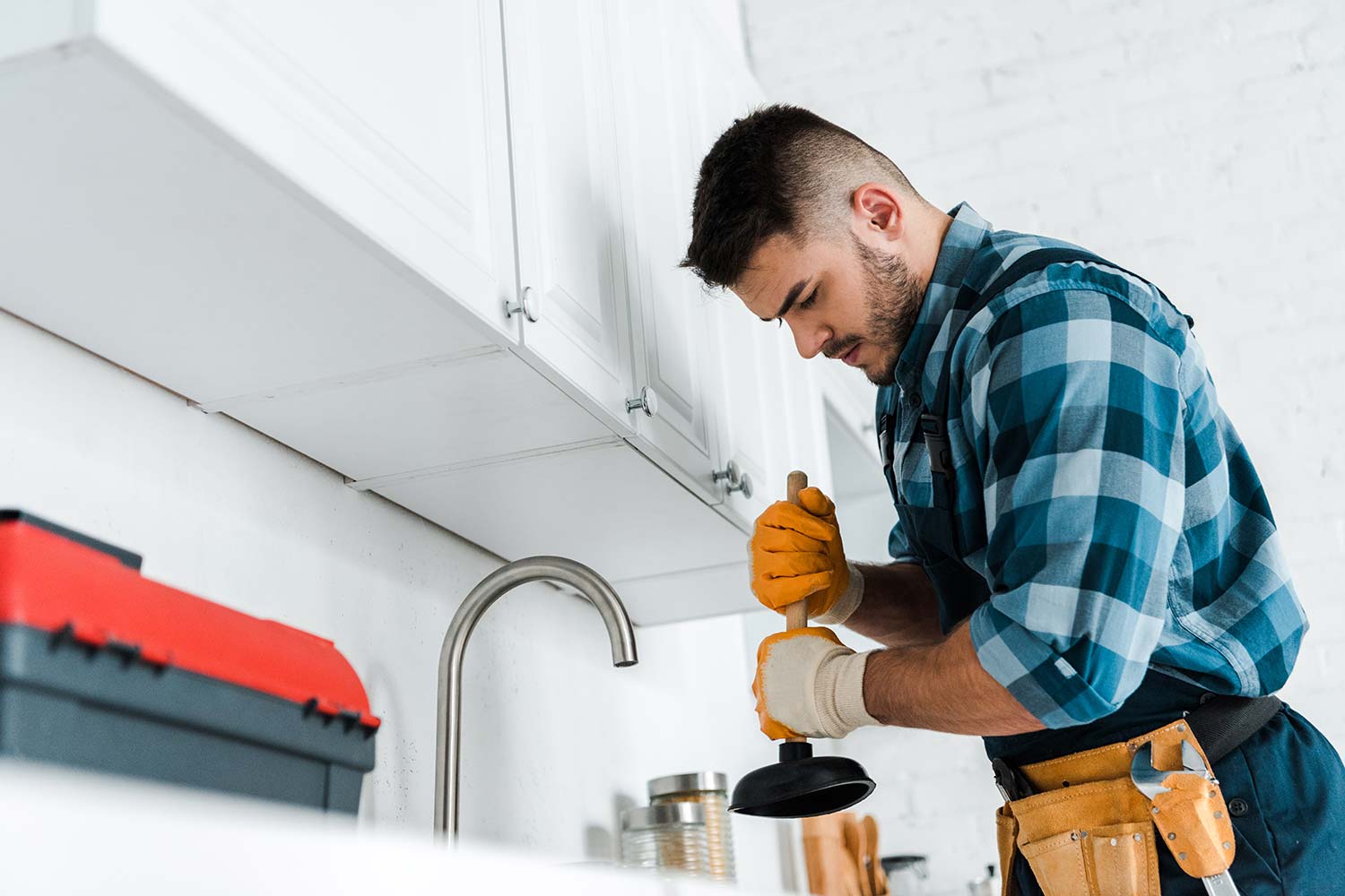 selective-focus-of-repairman-holding-plunger-in-ki-resize