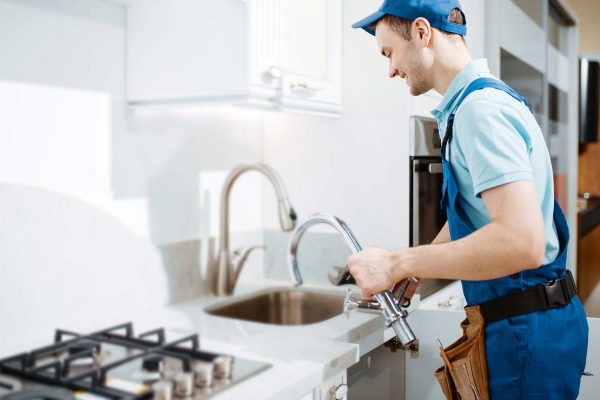 plumber-in-uniform-changes-faucet-in-the-kitchen-resize-1.jpg